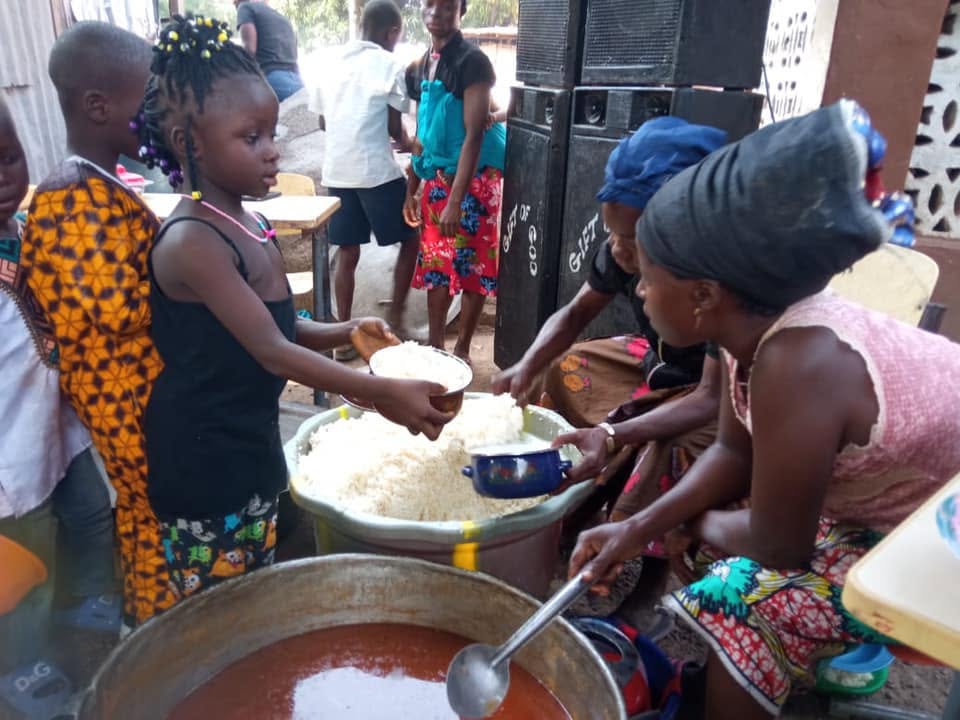 A child being served food from a large cooking pot